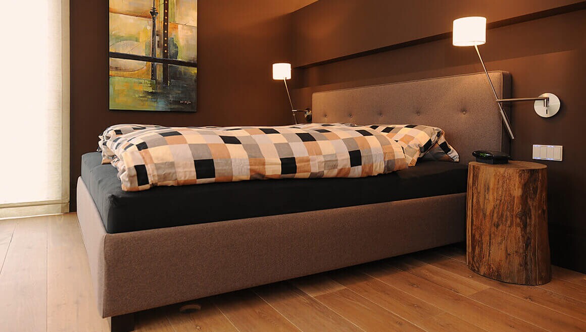 Schlafzimmer mit Ankleide hinter dem Kopfteil des Bettes – erdacht und gemacht im Tischlermeisterbetrieb Korfmacher.